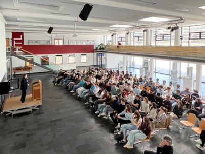 Roman Höllbacher (Künstlerischer Leiter Initiative Architektur) spricht vor Schüler*innen der HTL Saalfelden zur Abwicklung und Vergabe des Architekturpreis Land Salzburg.